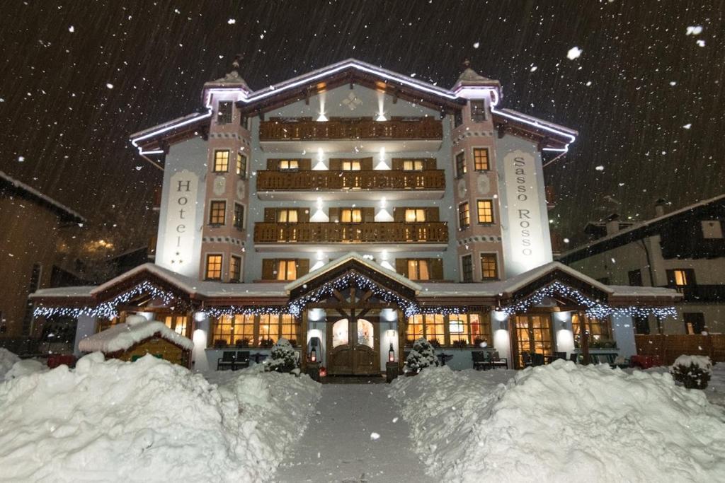 科姆梅扎杜拉Hotel Sasso Rosso的一座大建筑物,在晚上下雪