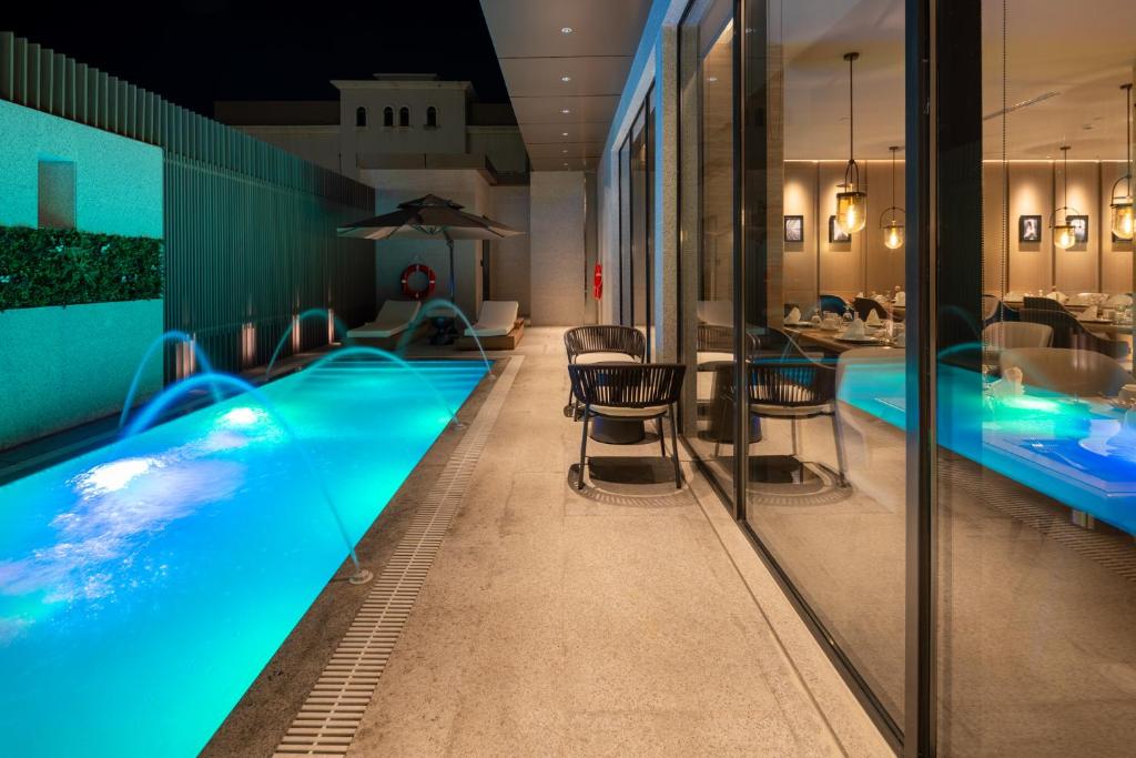 布赖代Boudl Al Rawdah的酒店游泳池设有椅子和桌子