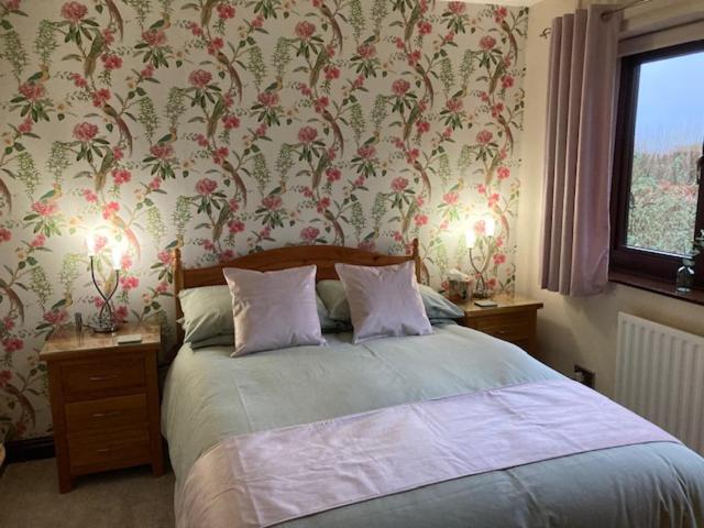 The Willows的一间卧室配有一张带花卉壁纸的床