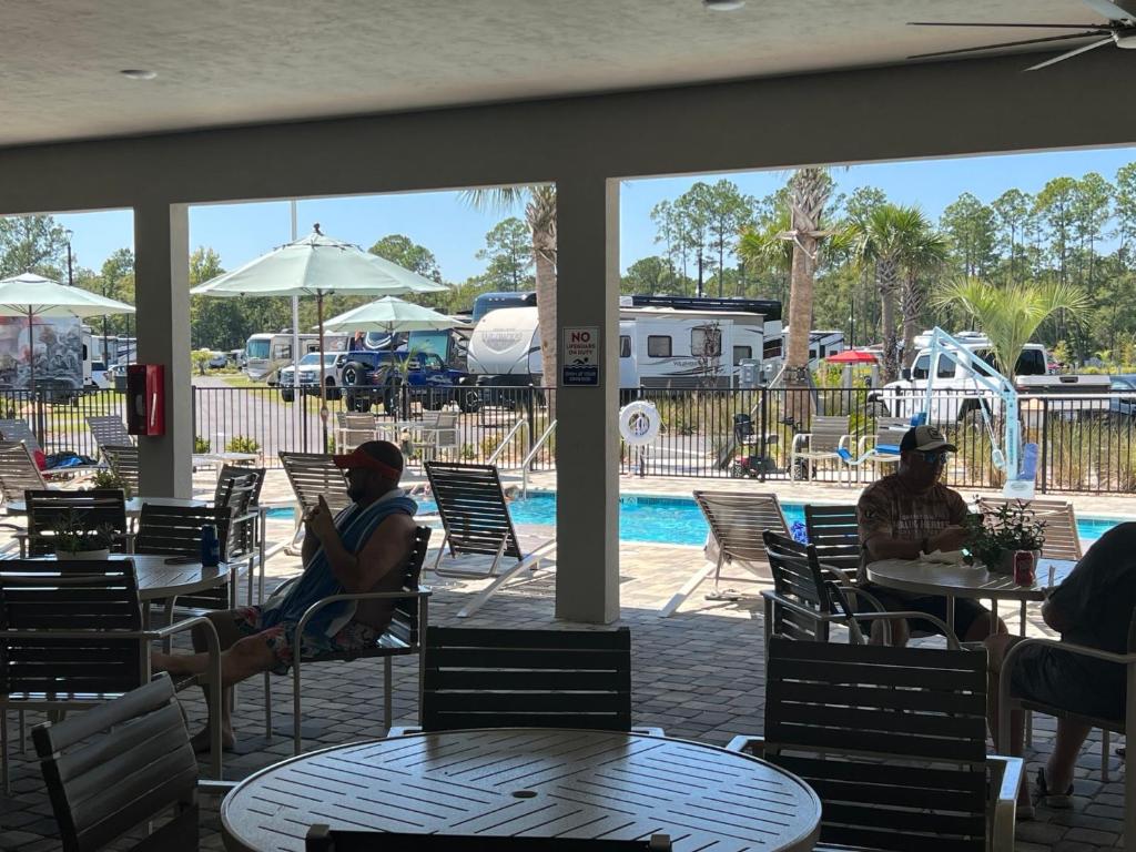 盖恩斯维尔Santa Fe Palms RV Resort的一群人坐在游泳池附近的桌子旁