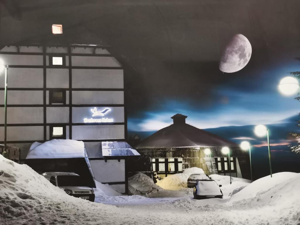 科帕奥尼克Hotel Srebrna lisica的一座在夜间被雪覆盖的建筑,月亮