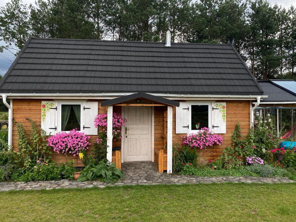 OsiekRóżana Zagroda Agroturystyka的一座带黑色屋顶和鲜花的小房子