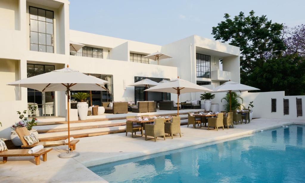 卢萨卡纬度15度酒店的一个带游泳池、桌子和遮阳伞的度假村