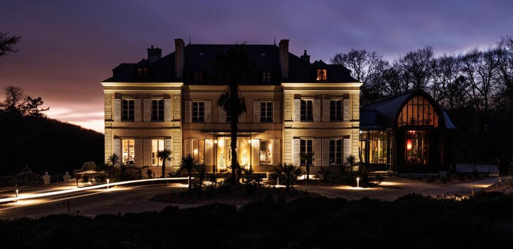 科尔维纳克Domaine de Locguénolé & Spa - Relais & Chateaux的夜晚有灯的大白色房子