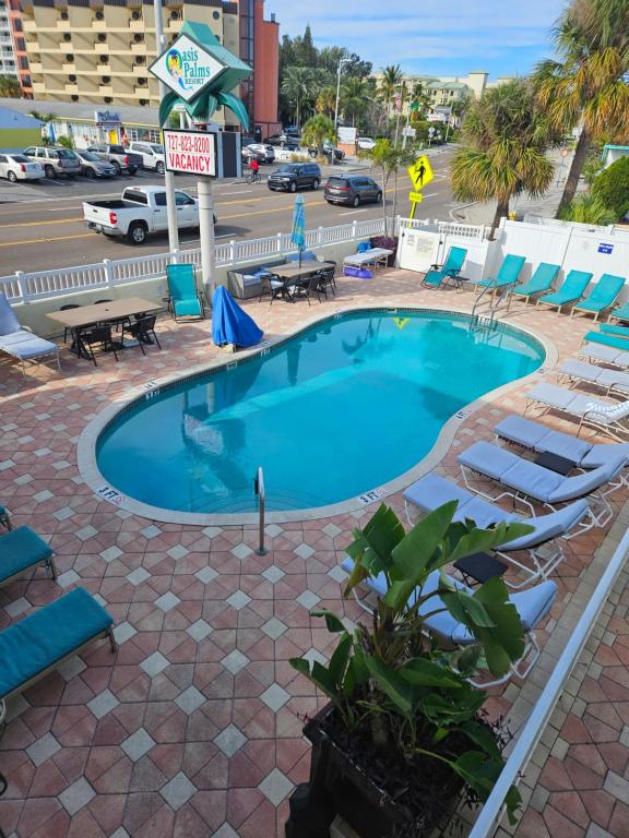 圣徒皮特海滩Oasis Palms Resort的一个带躺椅的游泳池以及停车场
