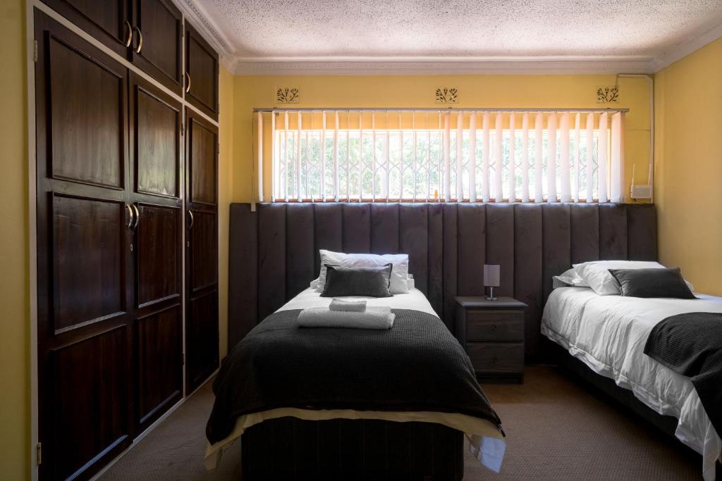 哈拉雷Hillview Holiday Condo的一间卧室设有两张床和窗户。