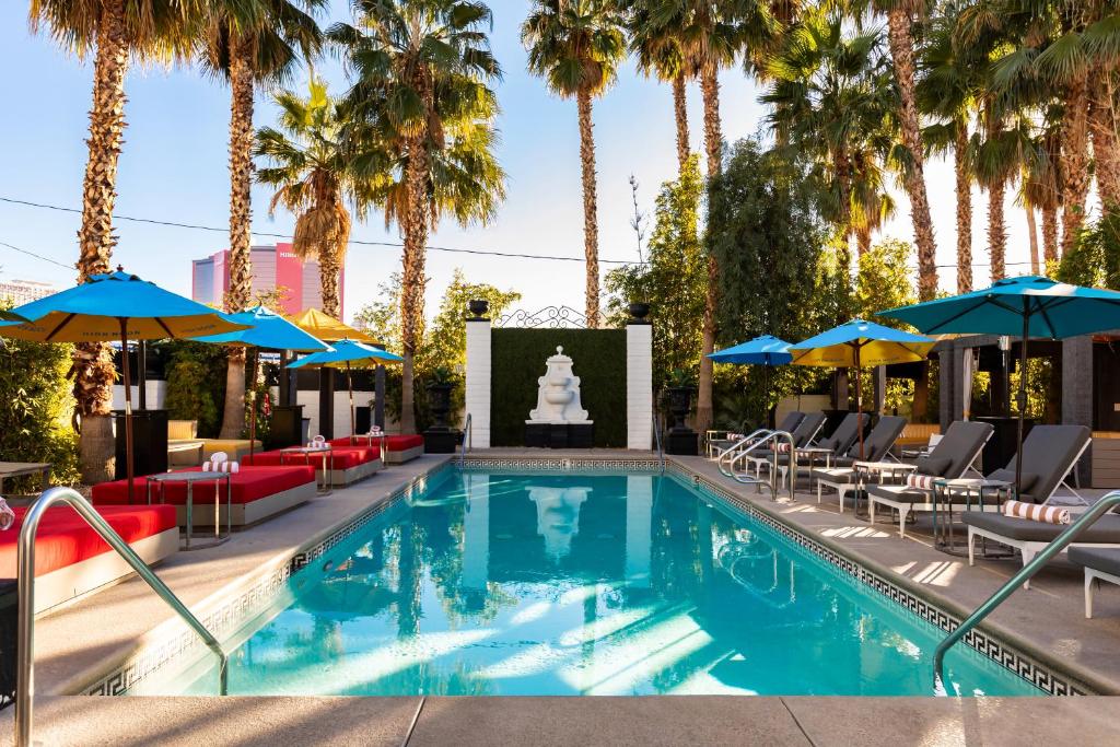 拉斯维加斯The Lexi Las Vegas的一个带椅子和遮阳伞的游泳池以及棕榈树