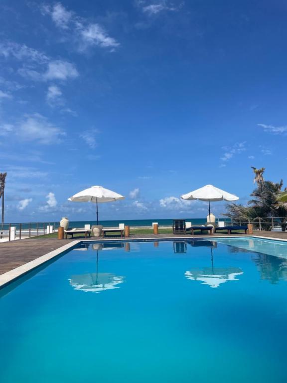 特赖里Villa Casa Ava Kite - Guajiru的一座带遮阳伞的游泳池,其背景是大海