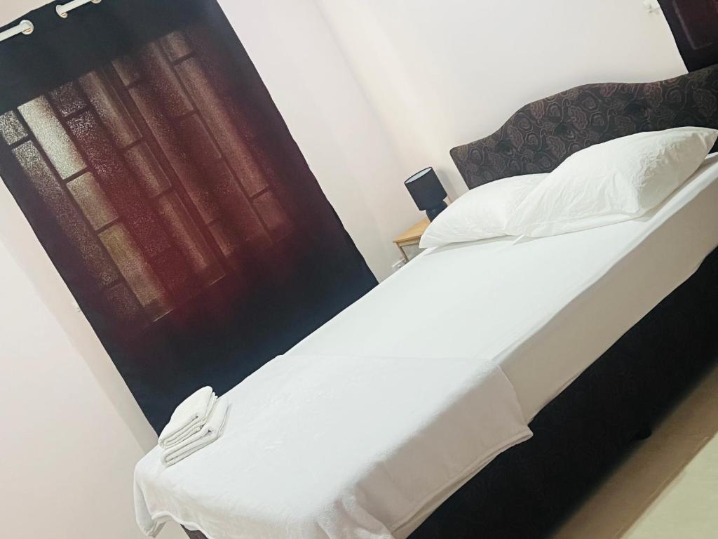 苏瓦Oxford Apartments Suva (2Bedrooms)的一间卧室配有一张带白色床单的床和一扇窗户。