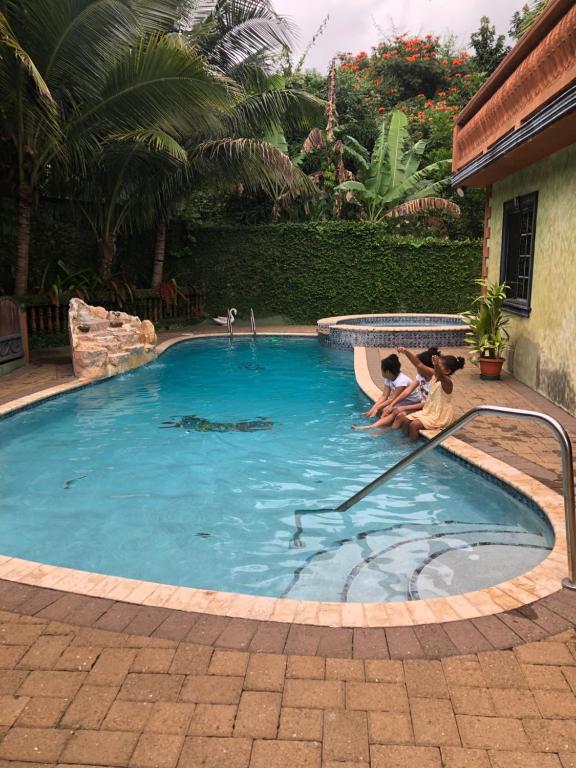 曼德维尔Hidden Oasis in Mandeville的水中一个游泳池,有两人坐在那里