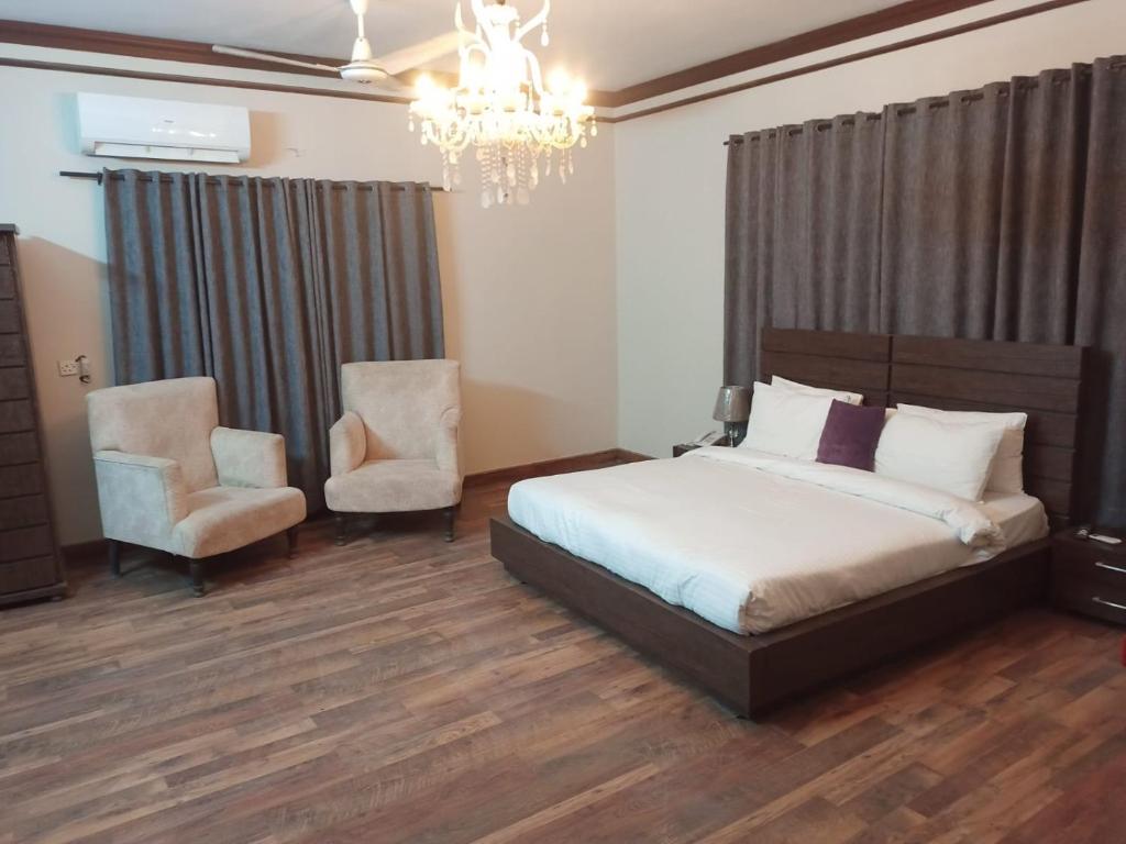 卡拉奇Bondi Beach Resort的一间卧室配有一张床、两把椅子和一个吊灯
