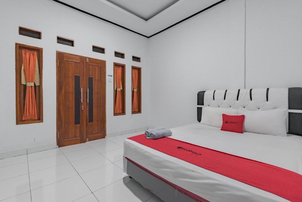 西洛瓦RedDoorz @ Geopark Ciletuh Sukabumi的白色的客房配有一张带红色毯子的大床