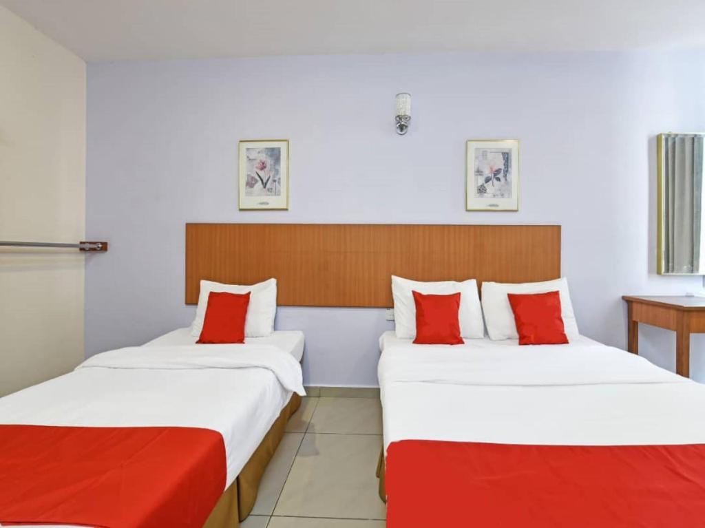 马六甲MRC Hotel Melaka Raya的两张位于酒店客房的床铺,配有红色枕头