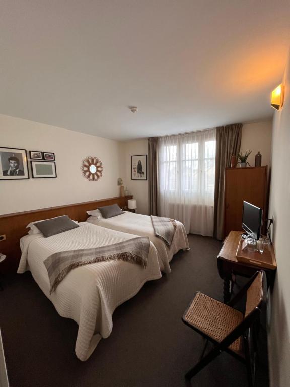沙罗勒Le Téméraire Hôtel的酒店客房配有两张床和一张带笔记本电脑的书桌