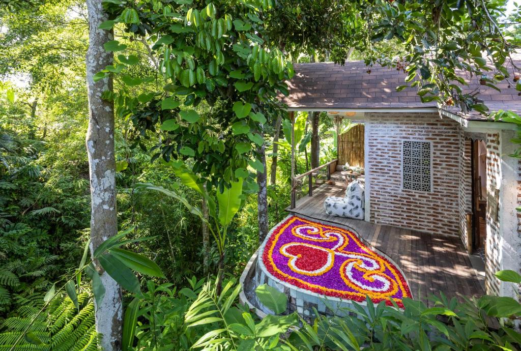 帕洋安Sacred Canyon Ubud by Pramana Villas的门廊上铺着色彩缤纷的地毯的房子