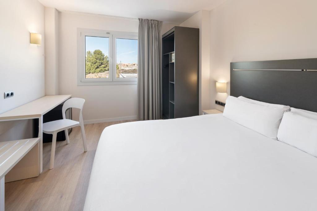 鲁维B&B HOTEL Barcelona Rubí的白色的卧室设有床、书桌和窗户