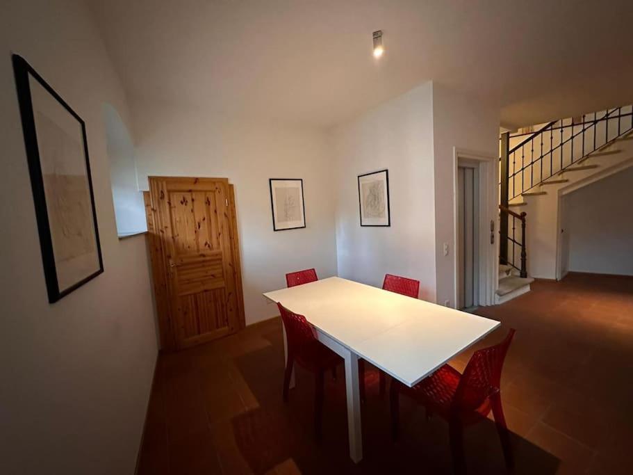门德里西奥Rancate charme apartment的一间设有白色桌子和红色椅子的用餐室
