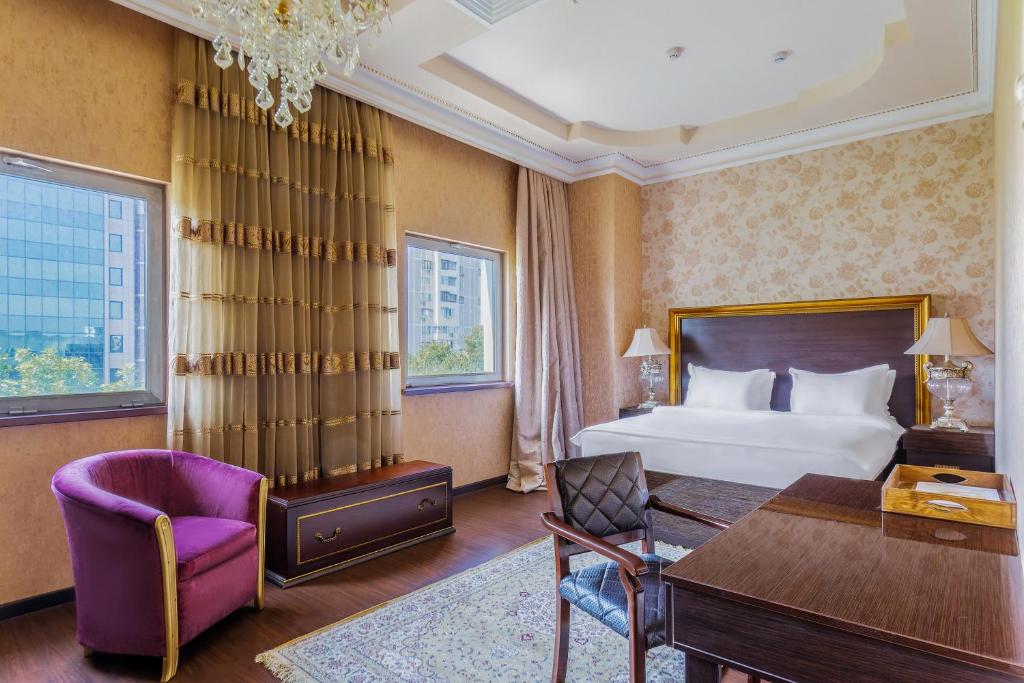 塔什干达尔罕精品酒店的酒店客房,配有一张床、一张桌子和椅子