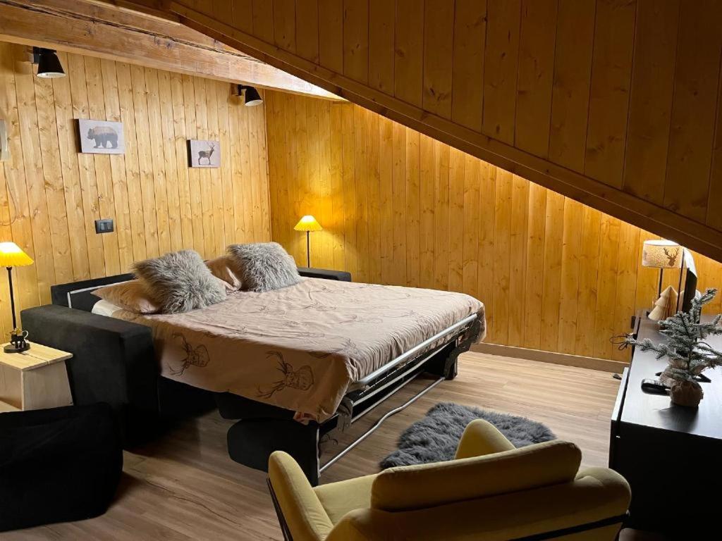 摩德纳迪-坎皮格里奥Mansarda delle Dolomiti nuovissimo appartamento的卧室配有一张床铺,位于带木墙的房间内