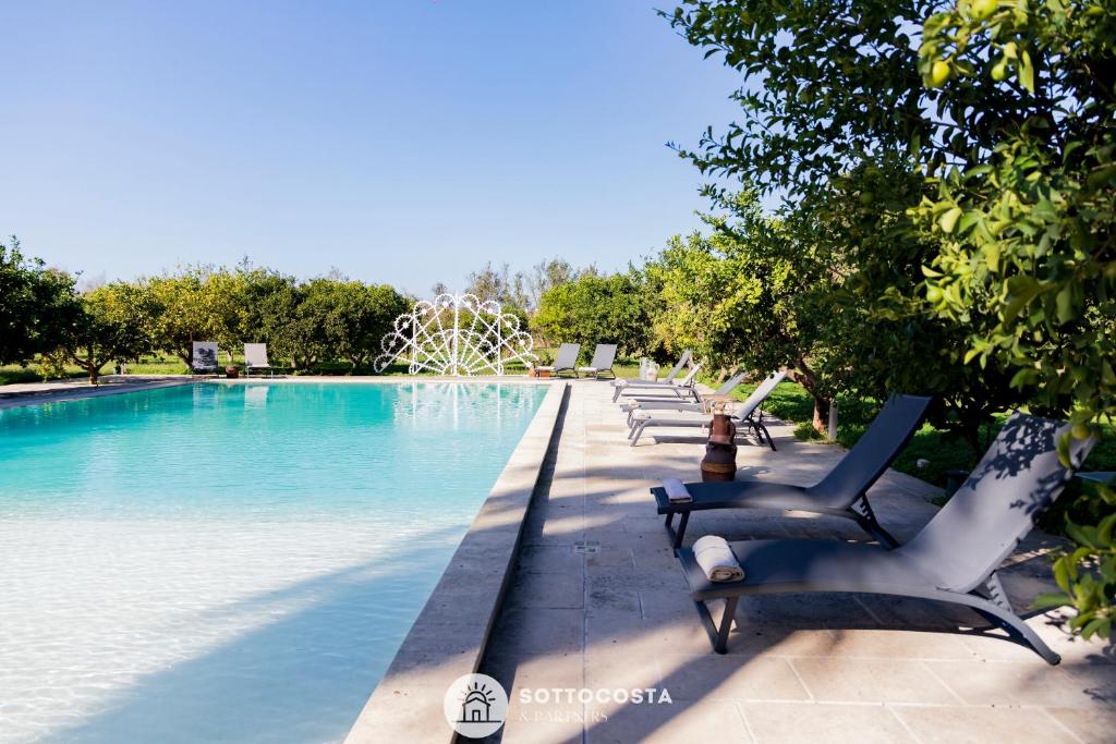 莱切省卡瓦利诺Masseria Tenuta Le Menze的游泳池旁的一排椅子