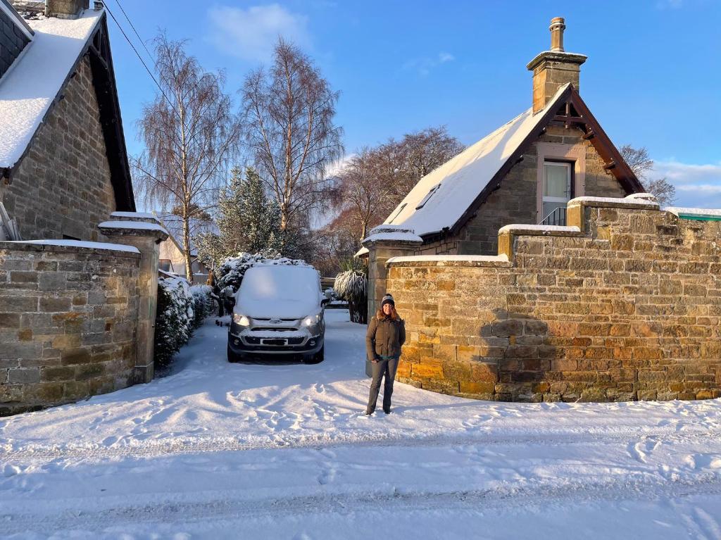 埃尔金Braemorriston Lodge的站在房子前的雪中站着的女人