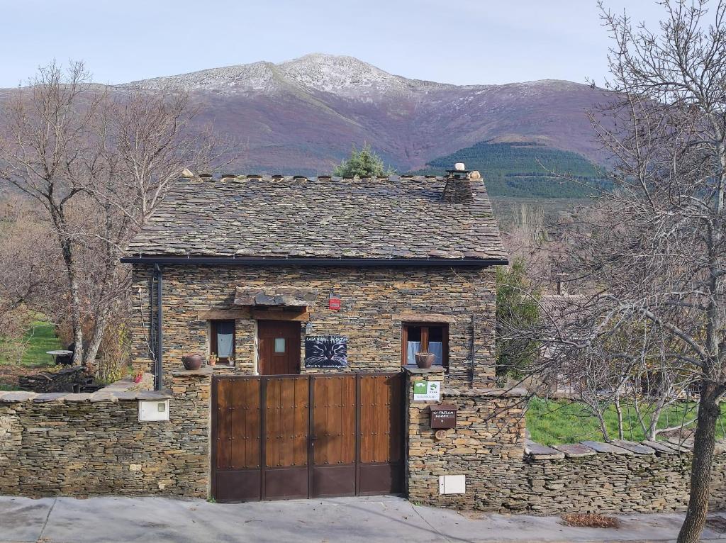 坎皮略德拉纳斯Casa rural La Gata的一座石头房子,设有木门和山