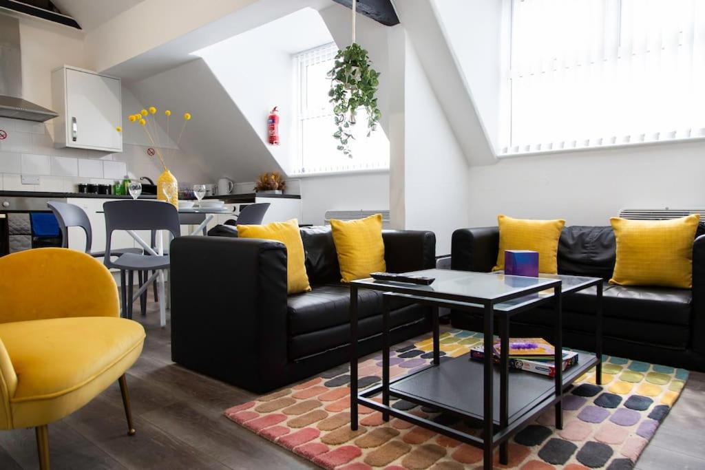 利物浦Bootle, Liverpool Trendy 1Bed Ft的客厅配有黑色沙发和黄色枕头