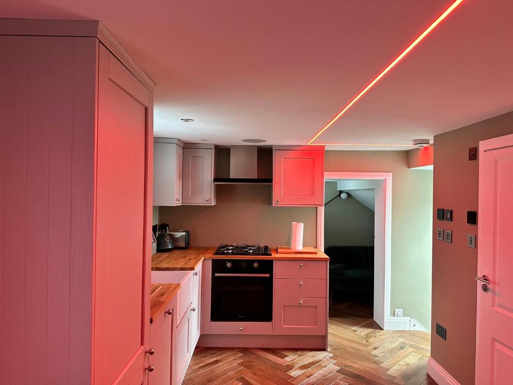 巴尔内特Super deluxe apartment的厨房配有粉红色的橱柜和天花板上的灯。