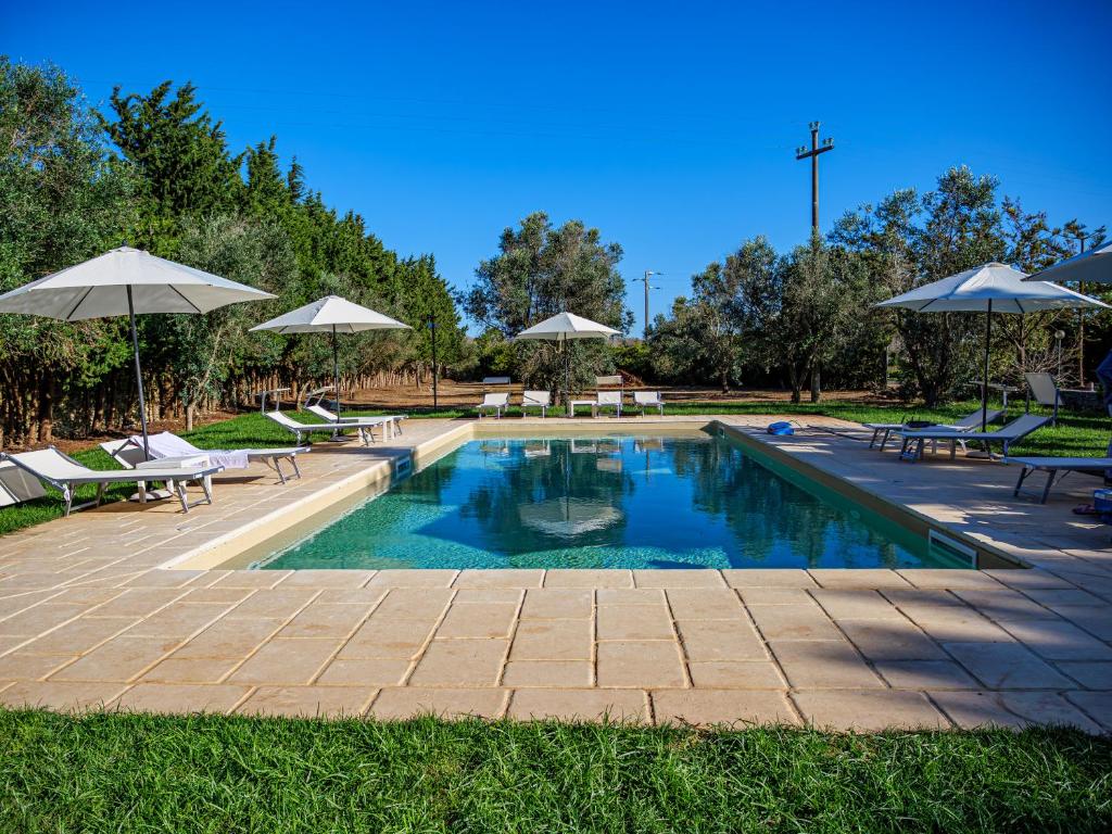 奥特朗托Masseria Fagà的公园内一个带椅子和遮阳伞的游泳池