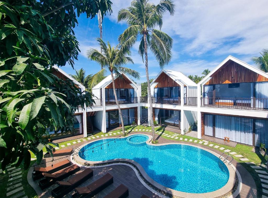 美奈Tuong Vy Boutique Hotel Mui Ne的一座带游泳池的度假村,位于一座建筑前