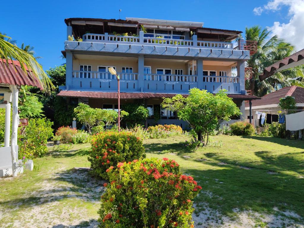 SolangonTropicasa Siquijor Seafront Guest House的一座大蓝色建筑,在院子里种花