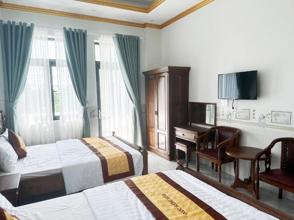 Chợ Phước HảiHotel Quốc Hương的酒店客房设有两张床、一张桌子和一台电视。