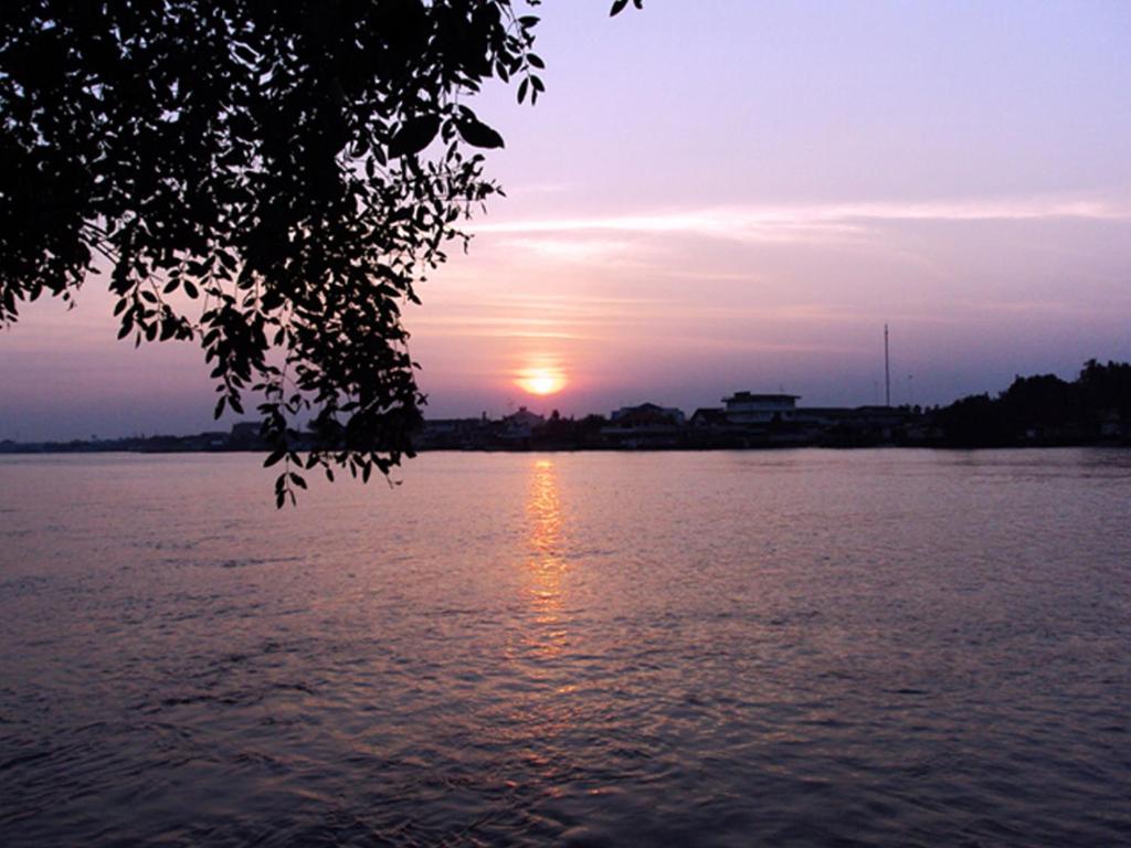 夜功府Baan Siriporn Resort - โรงแรมบ้านศิริพร รีสอร์ท的日落在水面上