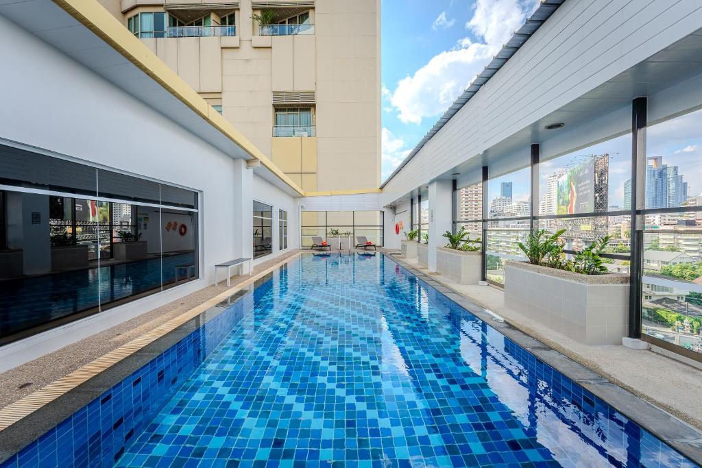 曼谷Citadines Sukhumvit 16 Bangkok的一座带窗户的建筑中的游泳池