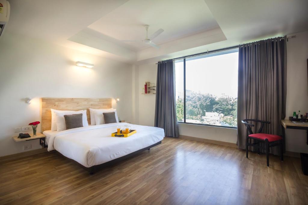 新德里Townhouse 013 New Friends Colony的一间卧室设有一张大床和一个大窗户