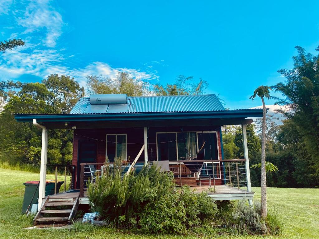 宁宾Nimbin waterfall retreat的田野上带绿色屋顶的小房子