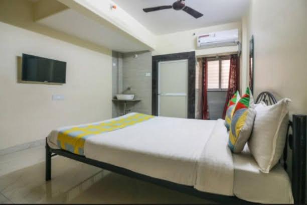 纳威孟买Cozy Stay Kharghar的一间卧室配有带枕头的床和电视。