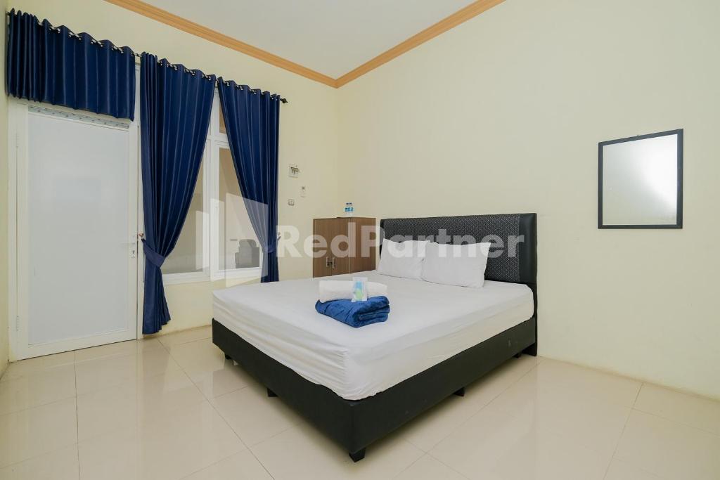 PaciranGrand Kencana Guesthouse near Wisata Bahari Lamongan Mitra RedDoorz的一间卧室配有一张带蓝色窗帘的大床