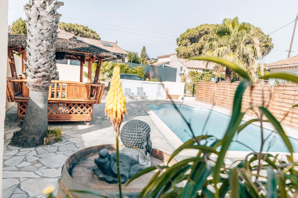 圣马克西姆Rêve D'azur, Plage à Pied, Piscine, Parking & Terrasse BBQ, Wifi et Draps Inclus en Bord de Mer à La Nartelle的花园设有一座雕像,毗邻一座游泳池