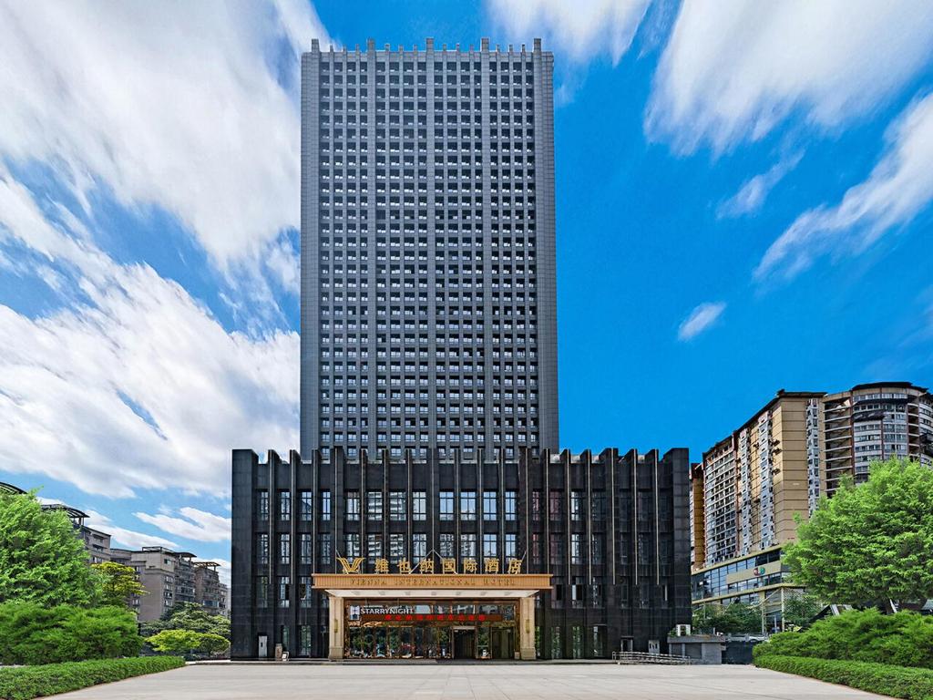 重庆维也纳国际重庆江北嘴金融中心酒店的一座高大的黑色建筑,前面有天篷
