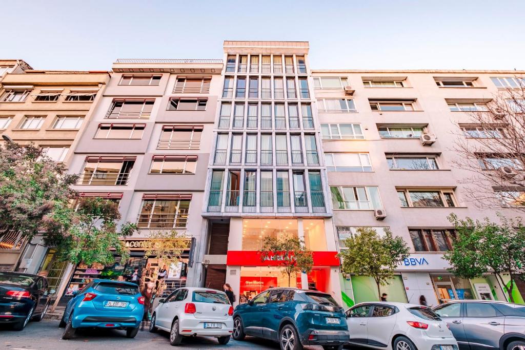 伊斯坦布尔Homie Suites - Luxury Apartments in Maçka的一座高大的建筑,前面有汽车停放