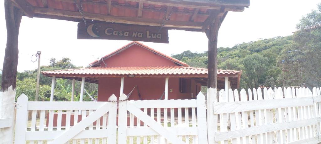 圣托梅-达斯莱特拉斯Casa na lua的一座红色的小房子,有白色的栅栏和标志