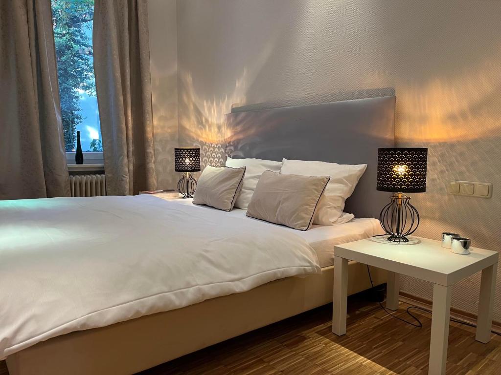 汉诺威Suite Appartement Friesenhof的卧室配有白色的床和带台灯的桌子。