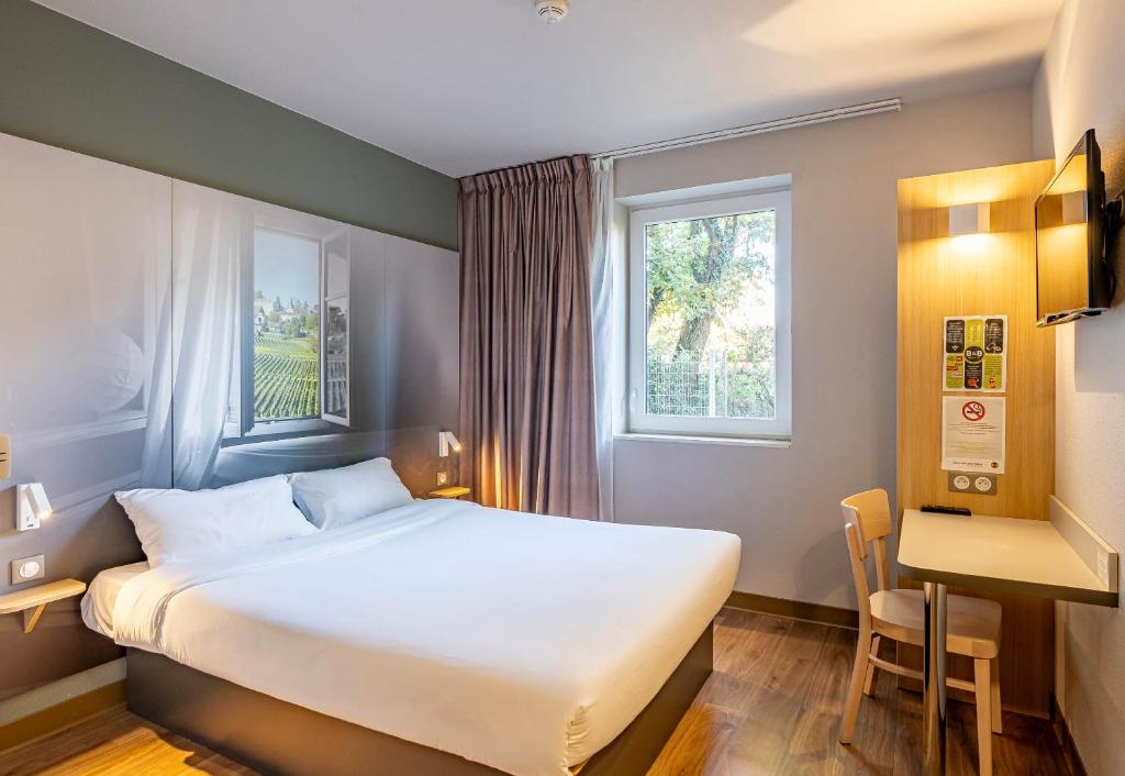 朗贡B&B HOTEL Bordeaux Langon的一间卧室配有一张床、一张书桌和一个窗户。