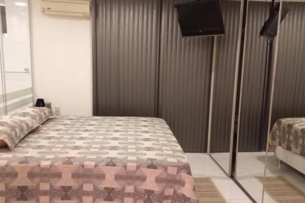 贝伦Loft em Belém的一间卧室配有一张床和一台平面电视