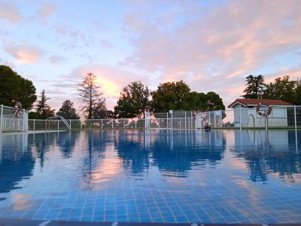 萨拉戈萨Albergue Zaragoza Camping的一个空的游泳池,背景是日落