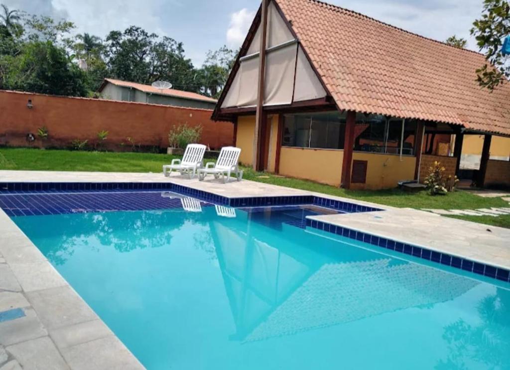 皮雷诺波利斯Recanto Rocas的一个带两把椅子的游泳池以及一座房子