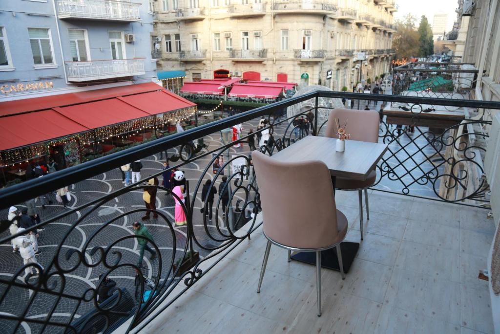 巴库Solo Hotel的阳台配有两把椅子和一张桌子,位于栏杆上