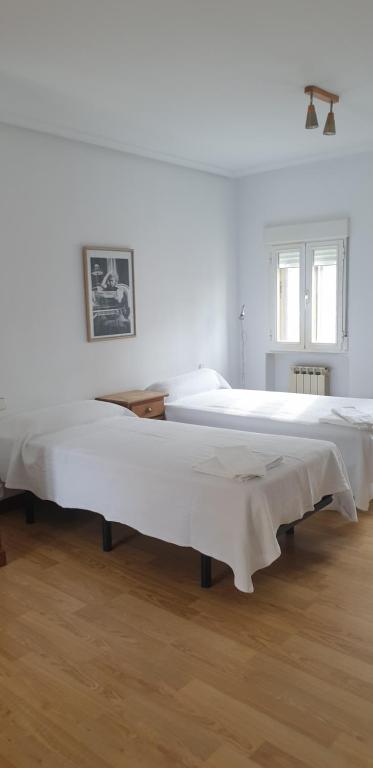 阿维拉Casa Telares Ávila的配有白色墙壁和木地板的客房内的两张床