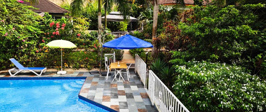 阿比让阿比让绿洲别墅旅馆的一个带蓝伞和桌椅的游泳池